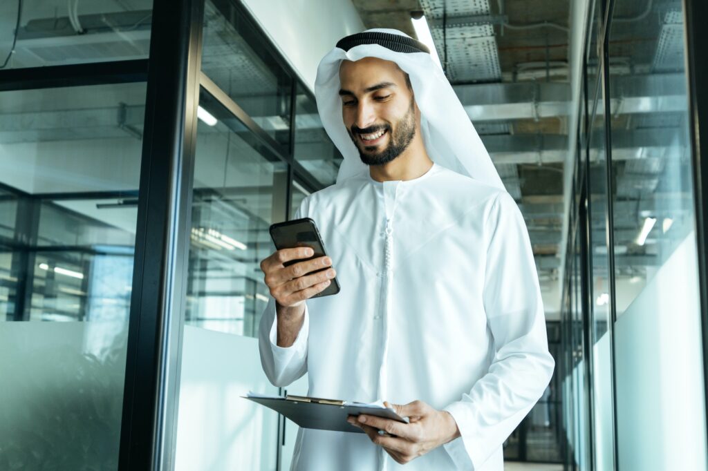 handsome man with traditional clothes working in an office of Dubai